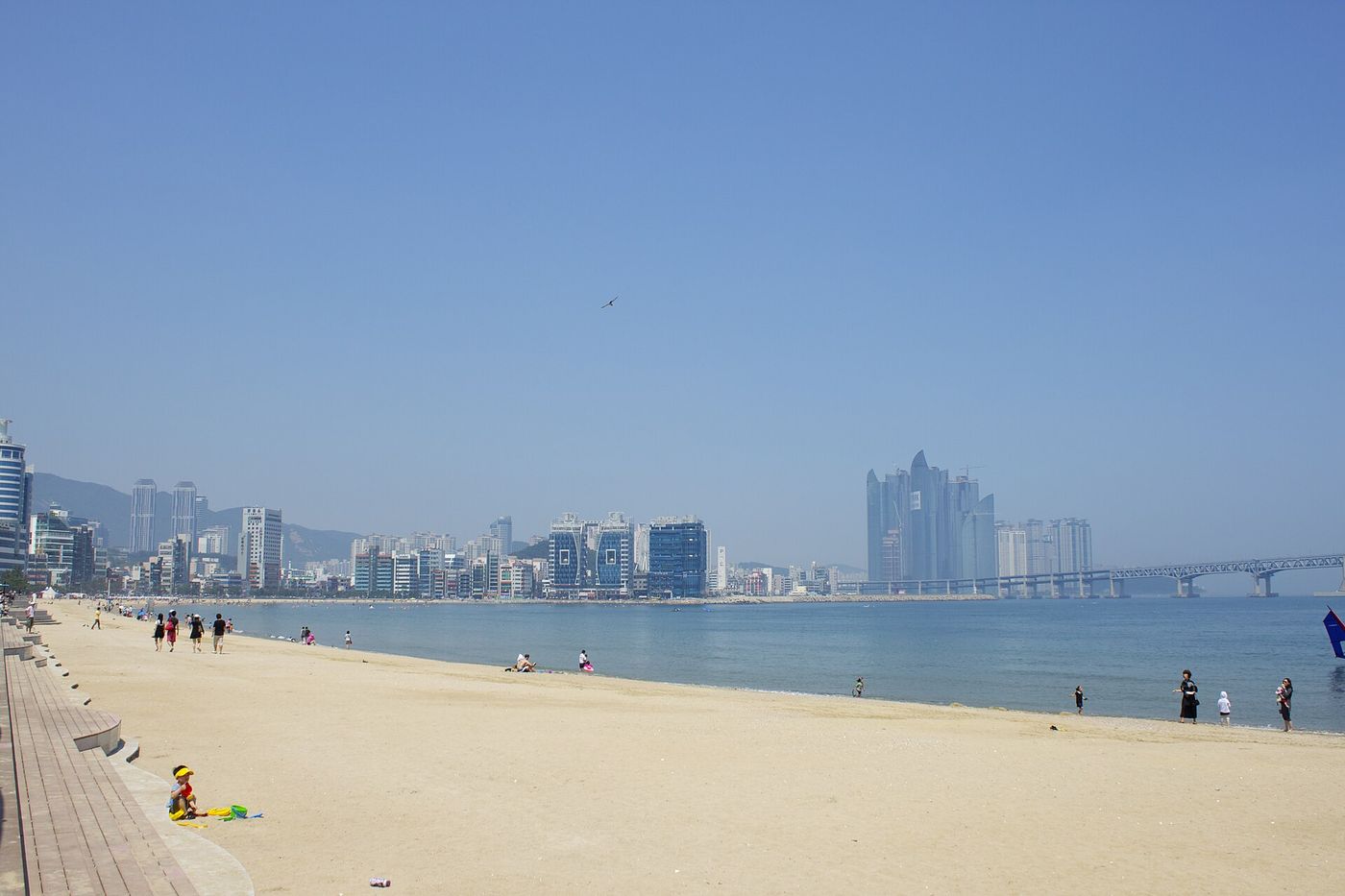 광안리해수욕장 백사장과 잔잔한 바다 너머로 원경처럼 걸친 광안대교