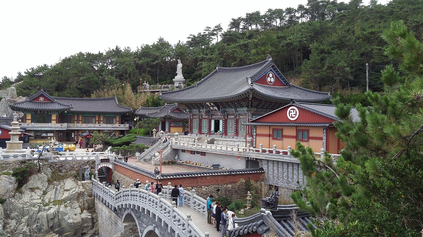 바닷가 절벽 위에 앉은 해동용궁사의 단청 전각들과 돌다리, 관음상