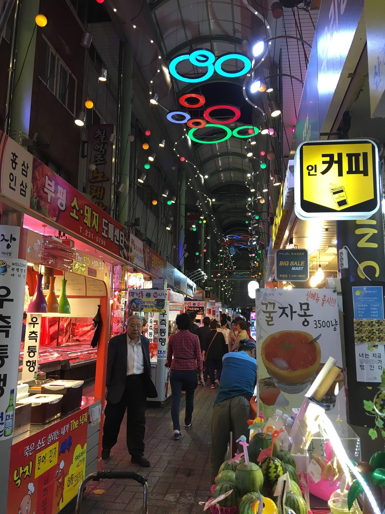 저녁의 부평깡통야시장 — 네온 아케이드 아래로 길거리 음식 좌판이 늘어선다