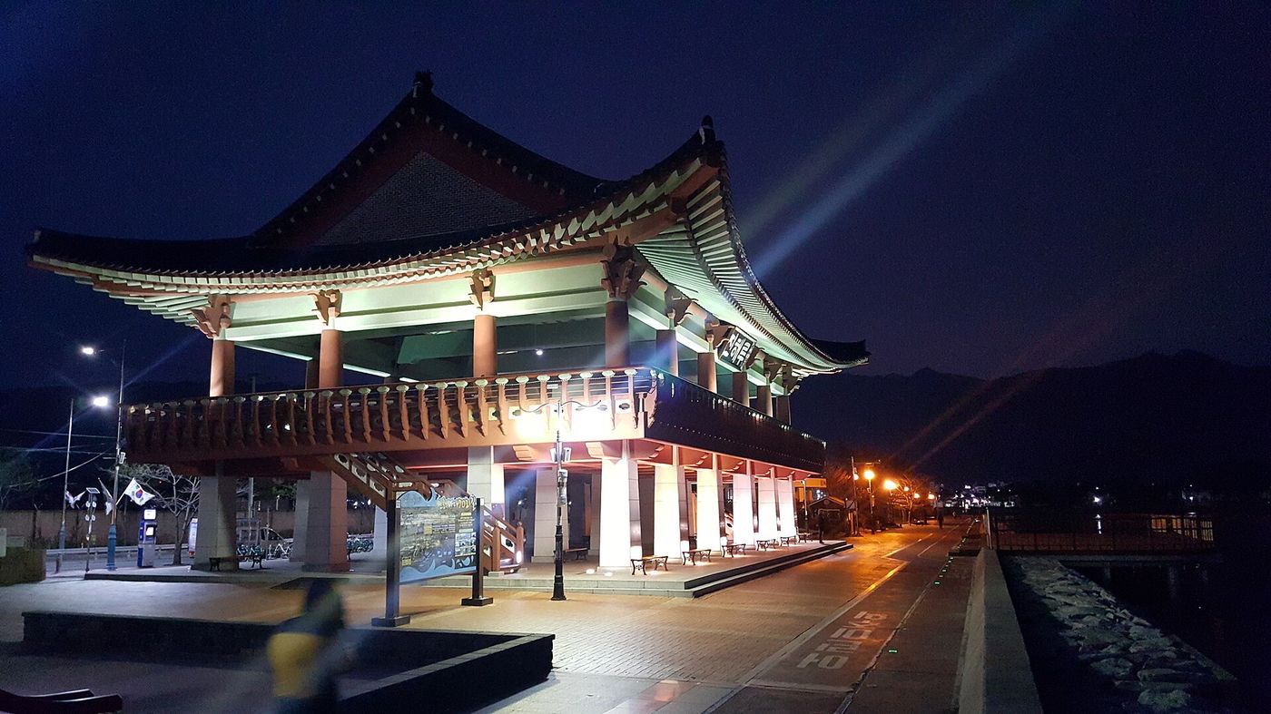 불을 밝힌 진해루 — 진해 바닷가에 선 팔작지붕 누각이 밤이면 조명을 두르고 물빛에 비친다
