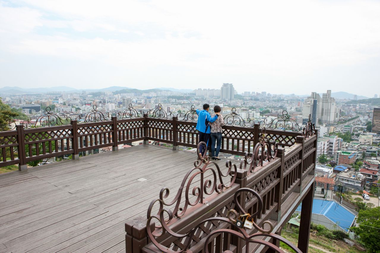 수암골 하늘전망대 — 우암산 자락 비탈 위 나무 데크에 오르면 청주 도심이 한눈에 펼쳐지고, 해 질 녘이면 시가지에 하나둘 불이 들어오는 야경 자리가 된다