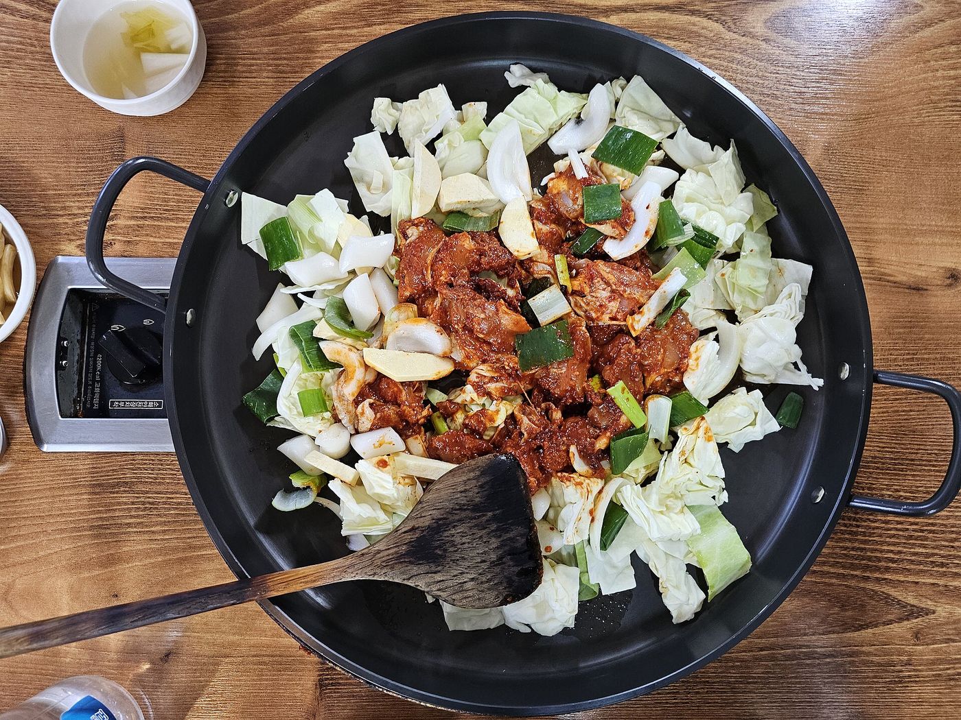 볶기 전의 닭갈비 한 판 — 막장 양념에 재운 닭다리살에 양배추·대파·마늘을 넉넉히 둘러 철판에 올린다