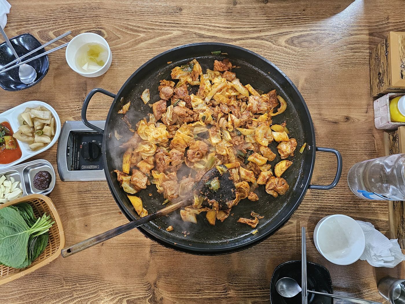 넓은 철판에서 볶이는 춘천 닭갈비 — 양념을 입은 닭과 채소가 한데 어우러져 김을 올리며 지글거린다