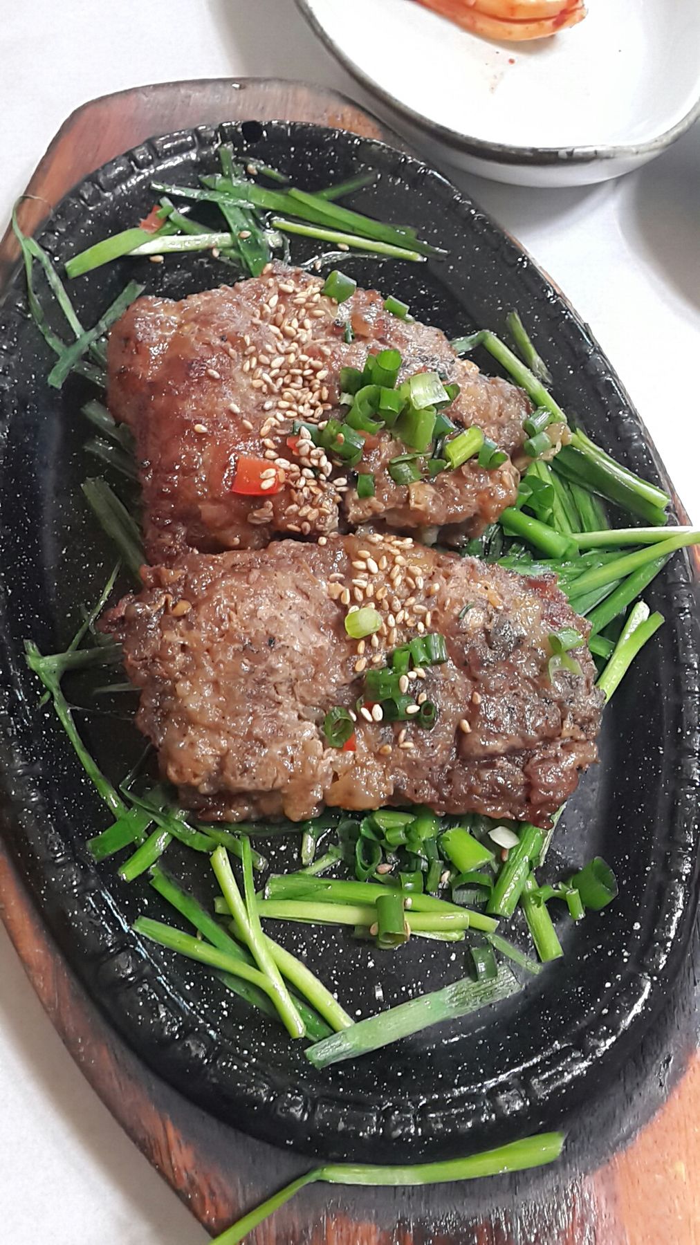 달군 무쇠판에 올린 담양 떡갈비 — 다진 고기를 도톰하게 빚어 구워 내고, 송송 썬 쪽파를 둘러 낸다