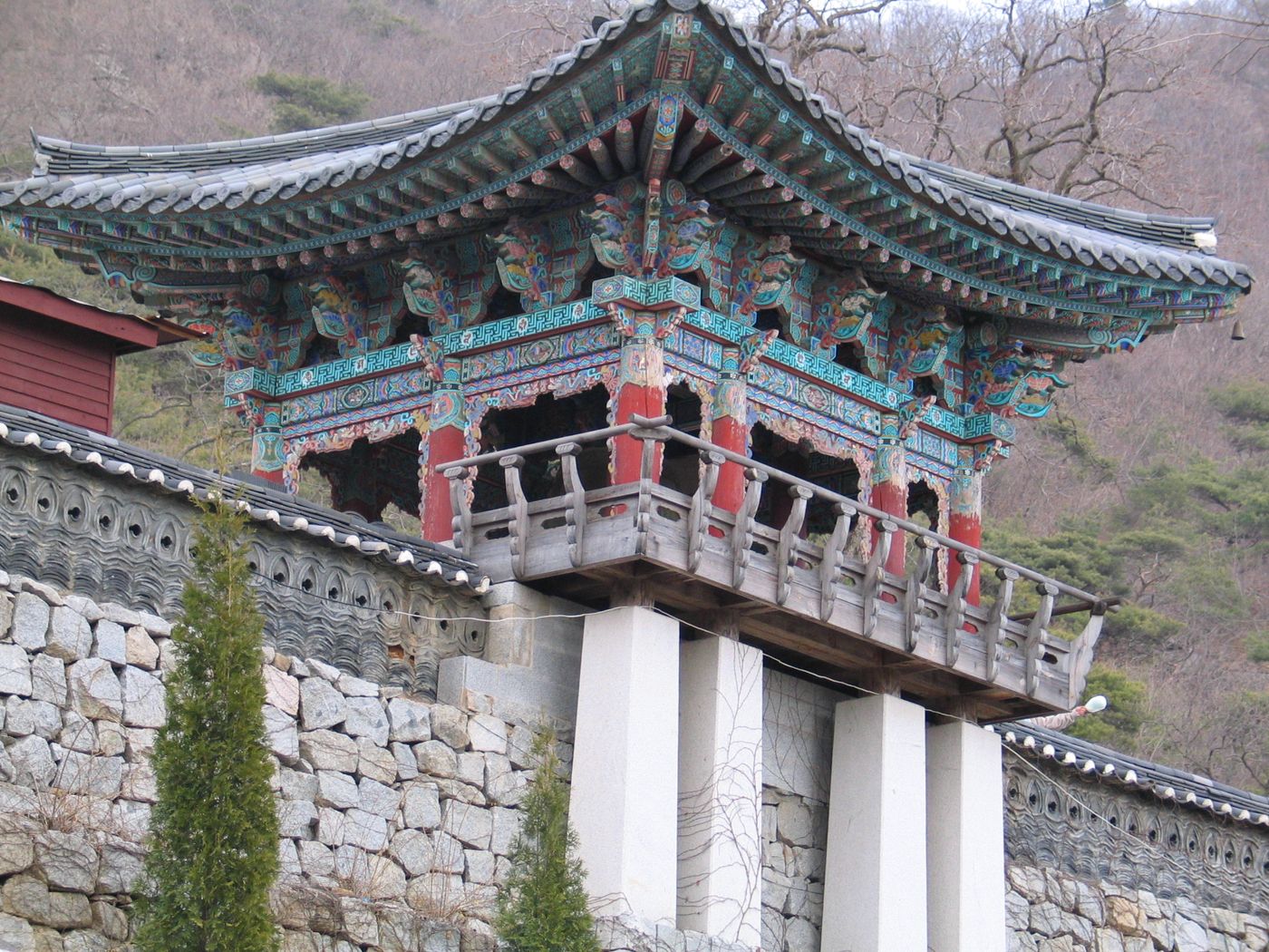 보문사 범종루 — 단청이 고운 누각 너머로 석모도의 산세가 이어진다