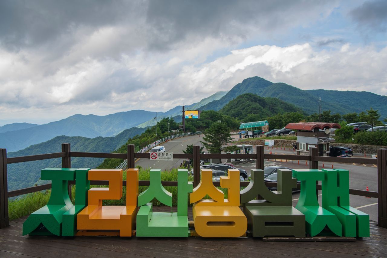 지리산 성삼재 표지석과 너른 주차장 — 차로 닿을 수 있는 가장 높은 고갯마루, 노고단으로 오르는 들머리다