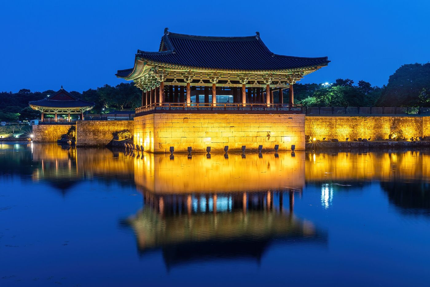 동궁과 월지 야경 — 조명을 받은 누각과 석축이 연못 수면에 통째로 겹쳐 아래로 한 채 더 선다