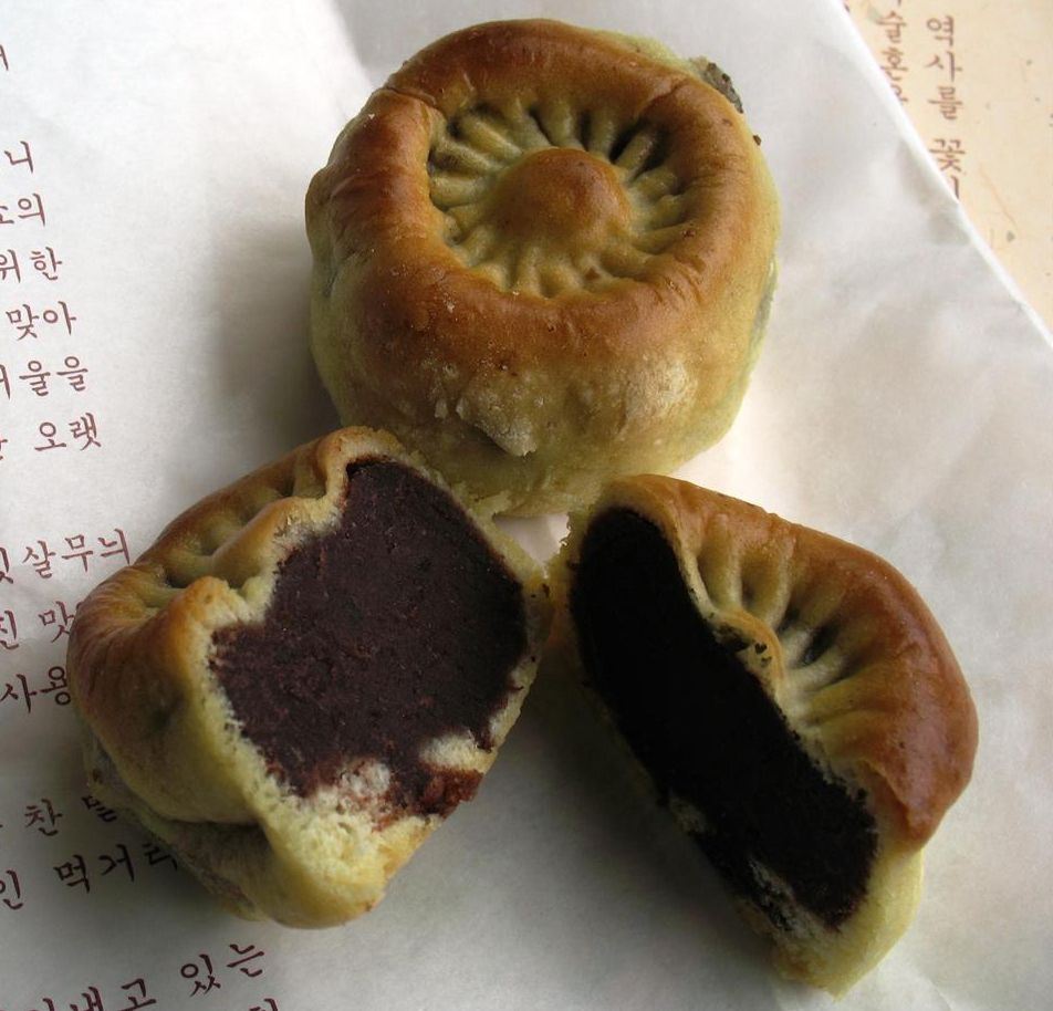 황남빵 클로즈업 — 반으로 가르면 검붉은 팥소가 가득, 윗면엔 국화꽃 무늬 도장이 찍혀 있다