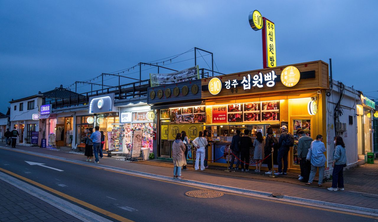 저녁 황리단길의 십원빵 가게 — 십 원짜리 동전 모양 빵을 사려고 사람들이 줄지어 선다
