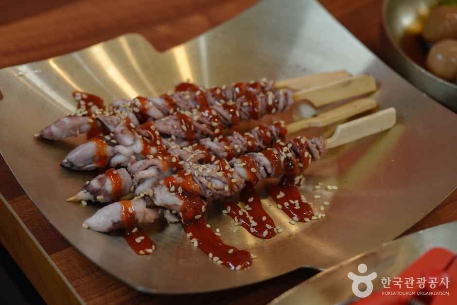 세발낙지 호롱구이 — 가는 발의 산 낙지를 나무젓가락에 돌돌 말아 양념을 입혀 구워 낸다