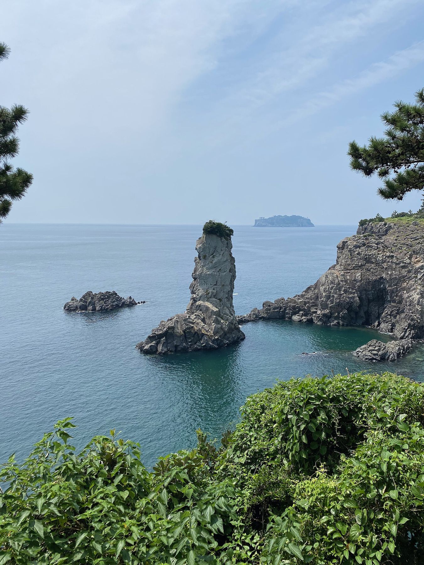 바다에 홀로 선 외돌개 촛대바위, 멀리 문섬이 떠 있다