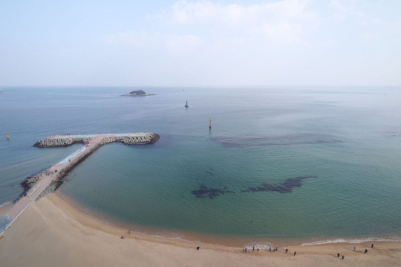 높은 곳에서 내려다본 동해안 백사장과 방파제, 앞바다에 떠 있는 작은 섬