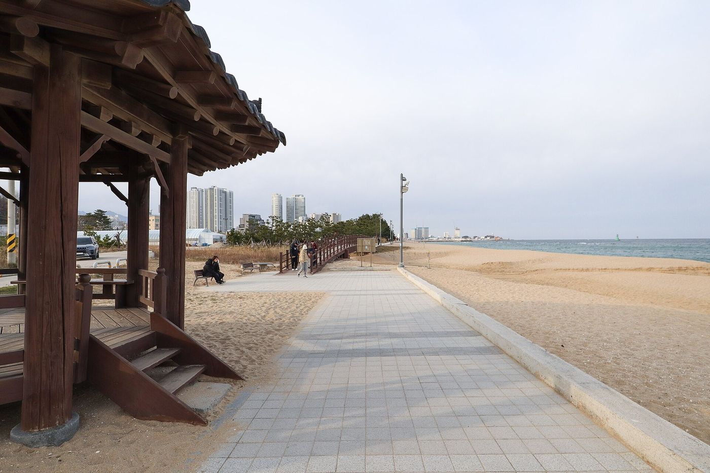 외옹치 바다향기로 — 백사장 곁 산책로에 자리한 전통 정자와 도심 풍경