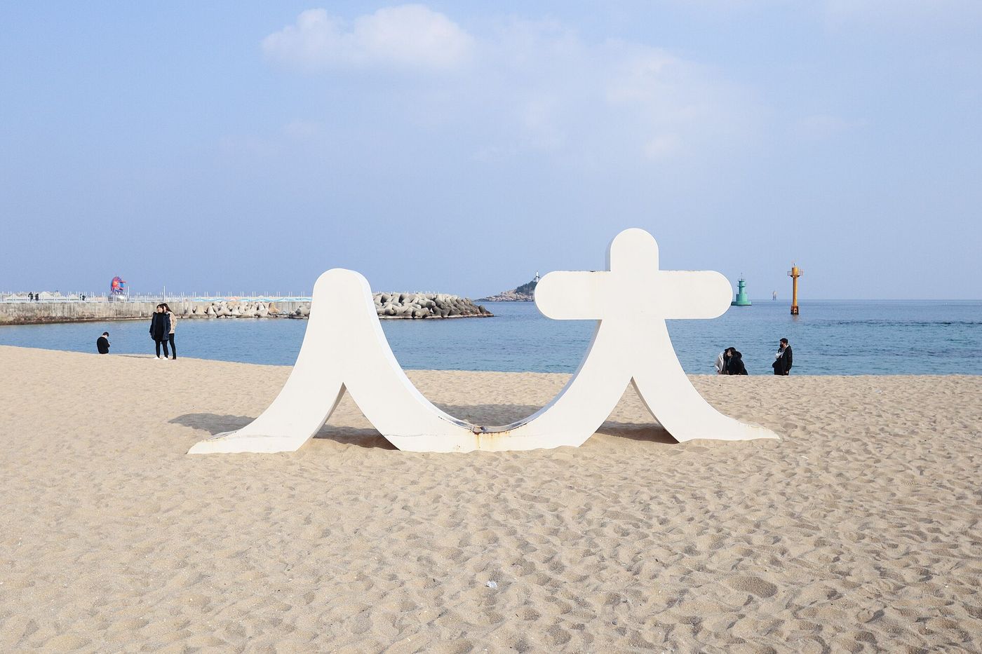 겨울 속초해수욕장 — 도심 건물과 맞닿은 너른 백사장에 잔잔한 동해 파도가 든다