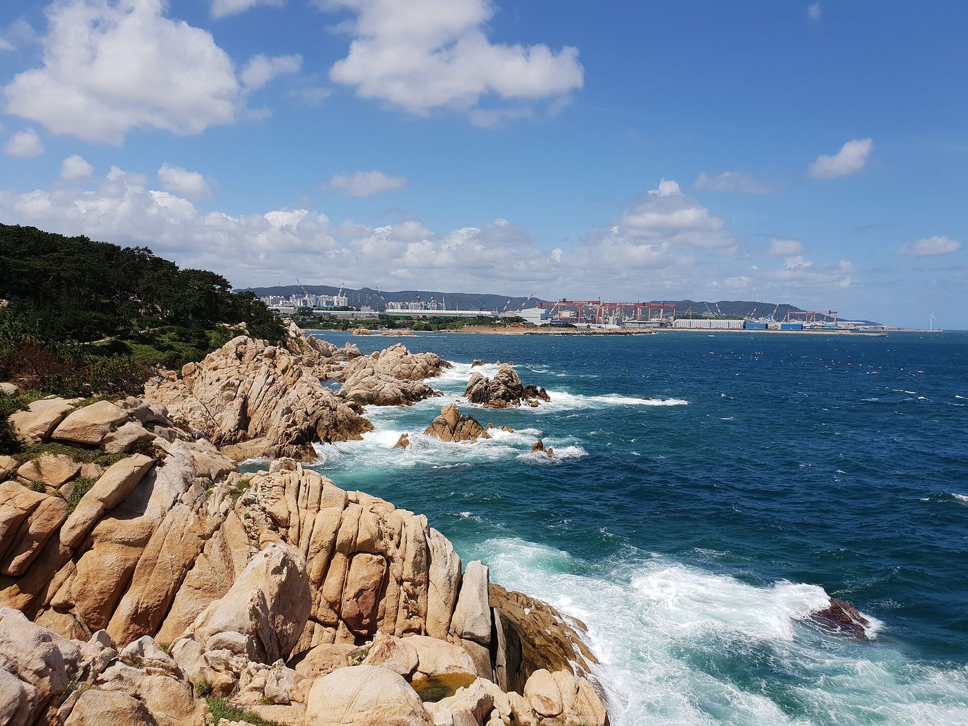주전 몽돌해변 — 검은 자갈밭에 파도가 밀려든다. 멀리 조선소 크레인이 울산다운 배경을 이룬다